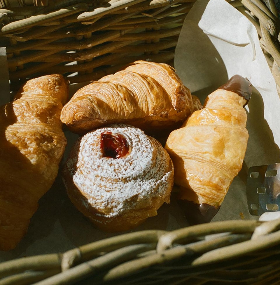Panier de pâtisseries artisanales avec croissant, canelé à la confiture de fruits rouges et pain au chocolat