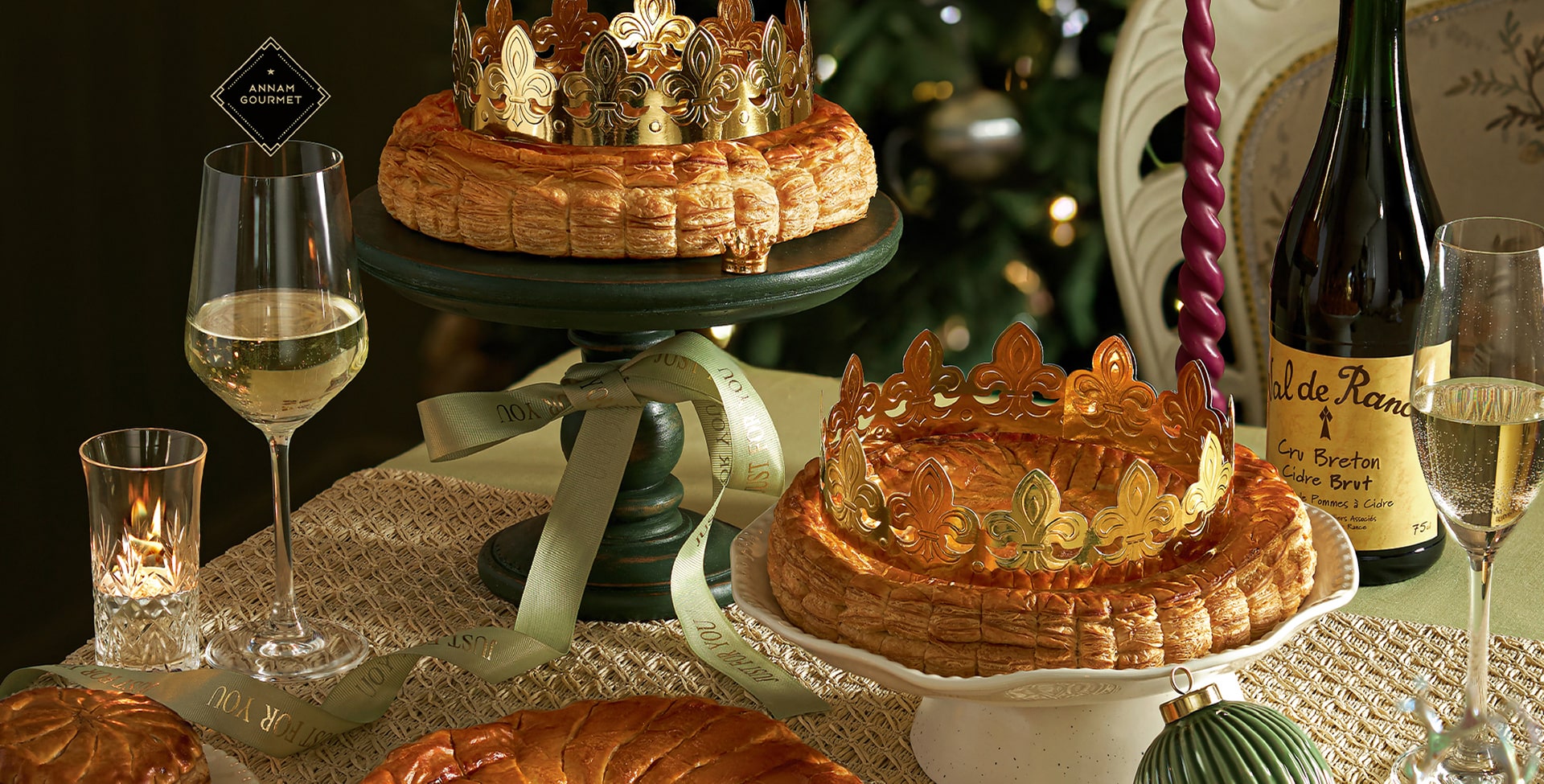 Table de fête avec deux galettes des Rois dorées couronnées, verres de champagne et cidre breton, décoration festive avec